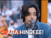 a man wearing headphones is singing into a microphone with the words aba hindeee written below him