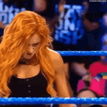 a woman with red hair is standing in a wrestling ring with a blue ring .
