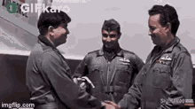 three men in military uniforms are shaking hands .