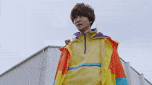 a young man wearing a yellow jacket and a purple hoodie