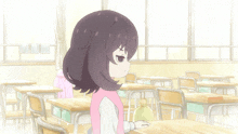 a girl in a pink shirt sits at a desk in a classroom