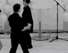 a man and a woman are dancing in front of a microphone with balloons that say ' a ' on them