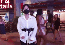 a woman wearing a face mask stands in front of a sign that says r & tails