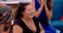 a woman is laughing while sitting on a couch in front of a group of people .