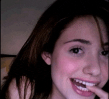 a close up of a woman 's face with a finger in her mouth