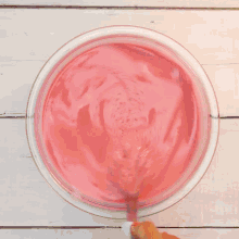 a person is mixing pink liquid in a glass bowl