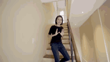 a woman in a black shirt is standing on a set of wooden stairs
