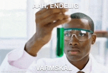 a man wearing goggles is looking at a green liquid in a test tube ..