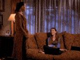two women are sitting on a couch talking to each other