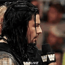 a wrestler is talking into a microphone while wearing headphones .