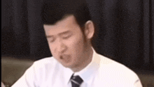a man in a white shirt and tie is sitting at a table .