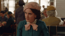a woman wearing a pink hat with the hashtag #mrs maisel behind her