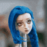 a close up of a doll 's face with blue hair