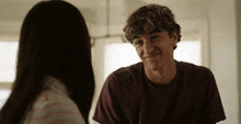 a young man in a maroon shirt smiles at a woman