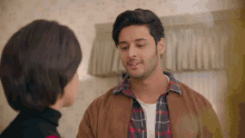 a man and a woman are looking at each other and the man is wearing a plaid shirt