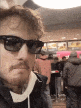 a man wearing sunglasses stands in front of a line of people