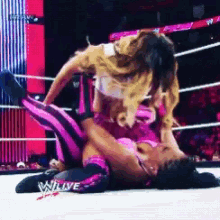 two women are wrestling in a ring with the word wlive on the bottom of the ring
