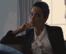 a woman sitting on a couch with her hand to her chin