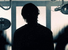 a silhouette of a person in a dark room with a light behind them
