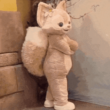 a stuffed animal dressed as a fox is standing in front of a wall .