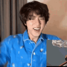 a young man wearing a blue shirt is laughing while looking at a picture of a mountain .