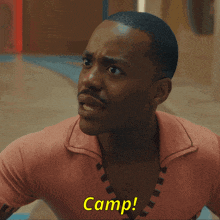 a man in a pink shirt with camp written on his chest