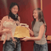 a woman holding a doll and another woman holding a yellow bag