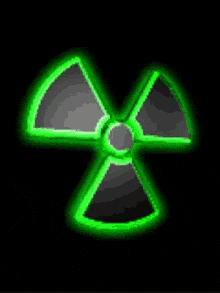 a green and gray nuclear symbol is glowing in the dark .