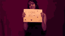 a woman is holding a piece of paper that says i love you