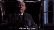 a man in a suit and tie is sitting in a chair .