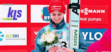 a person holding a bouquet of flowers in front of a sign that says ' bt ' on it