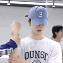 a man wearing a blue baseball cap and a white t-shirt is being held by another man .