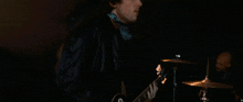 a man in a leather jacket plays a guitar