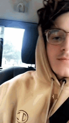 a young man wearing glasses and a hoodie with the letter d on the front