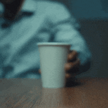 a person is holding a paper cup on a table