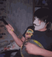 a man wearing a mask is holding a badminton racket and a cell phone