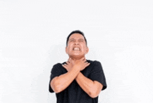 a man is holding his neck with his hands while looking up .