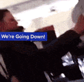 a blue sign that says we 're going down is above a person
