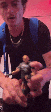 a man in a black shirt is holding a toy figure