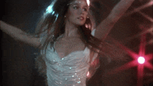 a woman in a white tank top is dancing in front of a blue light