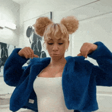 a woman with blonde hair is wearing a blue fur coat and a white tank top .