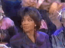 a woman in a purple jacket is sitting in a crowd of people .