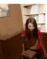 a woman in a red sweater is standing in front of a book shelf