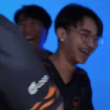 two men are standing next to each other and one of them is wearing glasses and earrings .