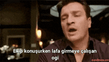 a man in a black shirt is speaking in a foreign language with the website makelmeme.com in the corner