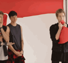 a group of young men standing in front of a large red flag