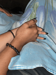 a person wearing a black bracelet holds another person 's hand on a bed