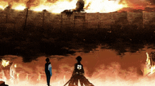 two people standing in front of a wall that is on fire and a giant statue of a man