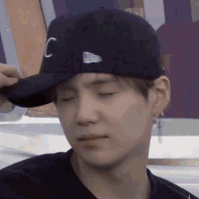 a close up of a person wearing a baseball cap and earring .