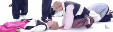 a group of people are kneeling on the ground and one of them is wearing a pink shirt